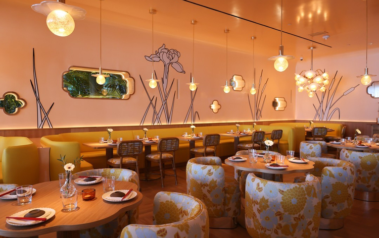 Modern restaurant interior with yellow walls, floral wallpaper, and hanging spherical light fixtures.